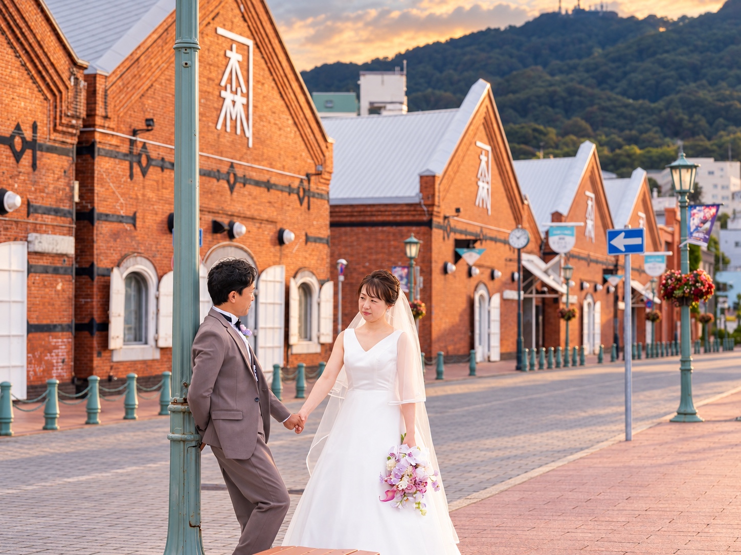 函館・金森赤レンガ倉庫群の前で、手をつないで向き合うウェディング姿のおふたりを撮影した実際の写真。